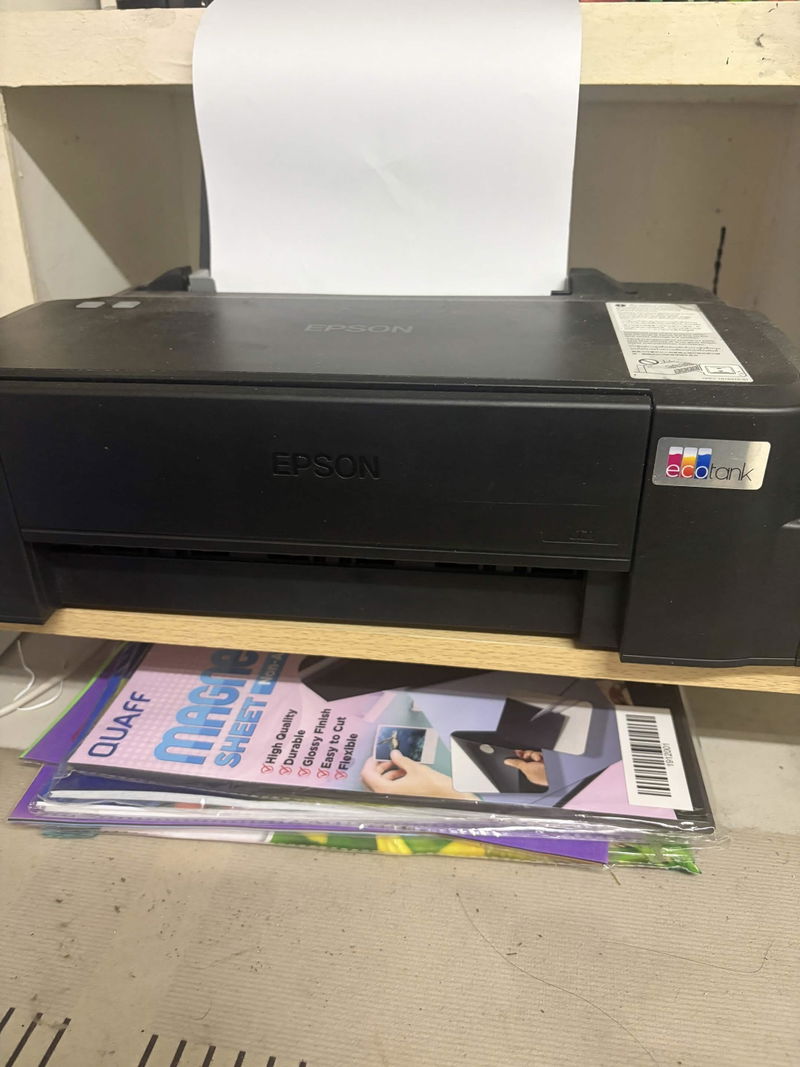 An Epson EcoTank printer sitting on the Plinth monitor riser with paper stored in the shelf underneath