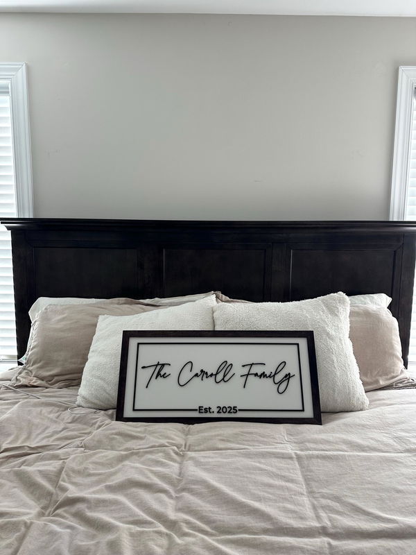 Customer photo: a framed sign reading The Carroll Family, Est. 2025, propped against the pillows of a bed.