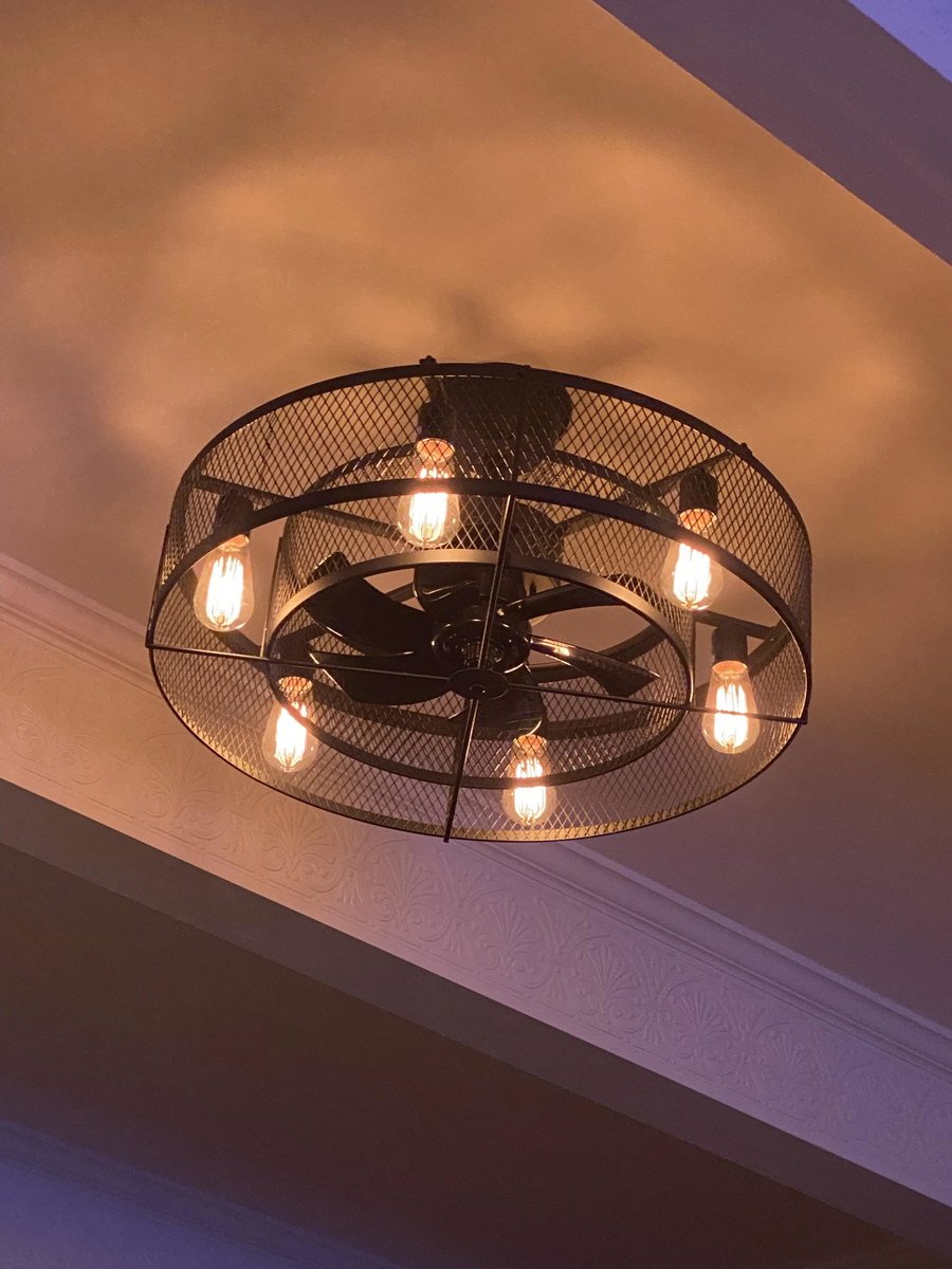 Customer-installed 26-inch caged ceiling fan glowing in a den