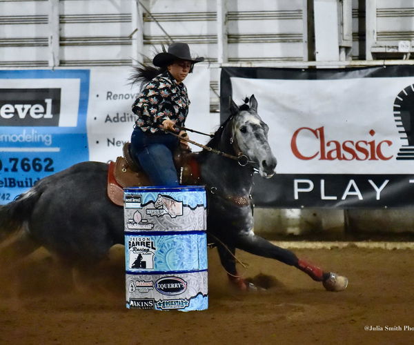 Barrel racer and horse turning a barrel in a rodeo arena