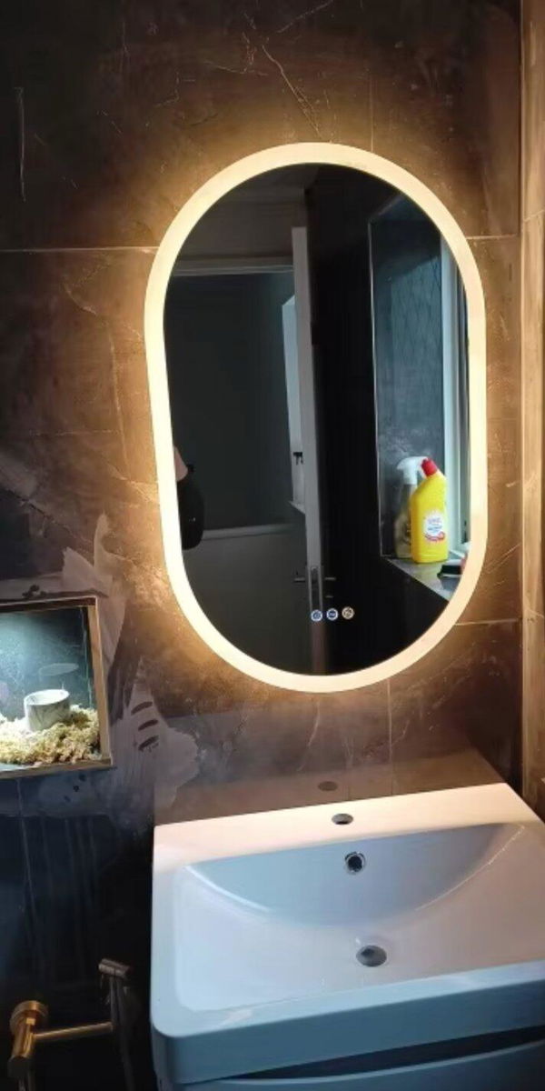 Customer photo of a warm illuminated oval mirror above a bathroom basin
