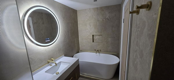Customer photo of a round illuminated mirror in a bathroom with a freestanding bath