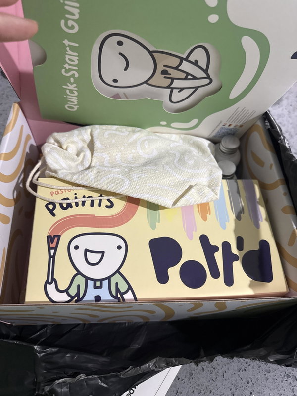 An opened Home Pottery Kit with tools and paints laid out