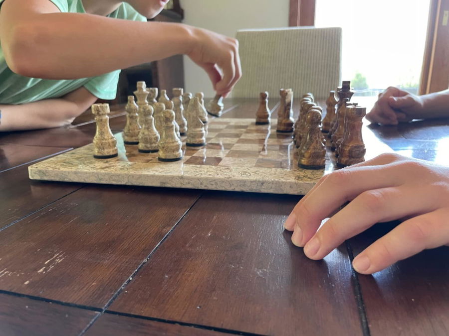 Child playing on a marble chess set at a table in a customer home