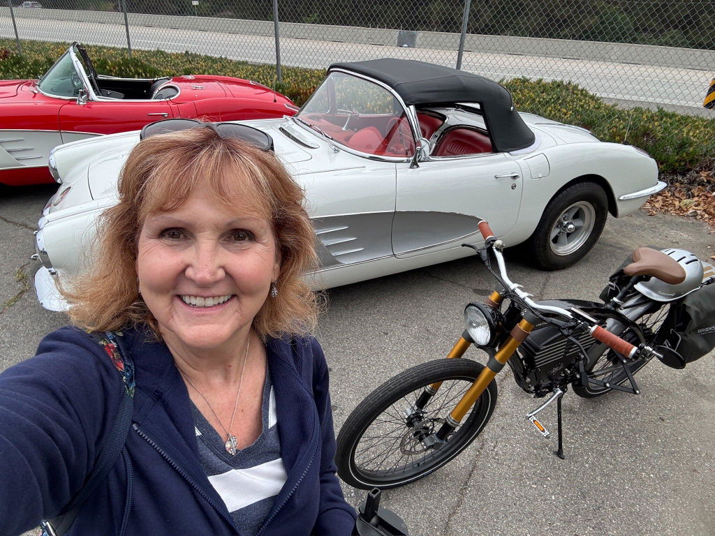 Customer selfie beside a Vintage bike and classic cars