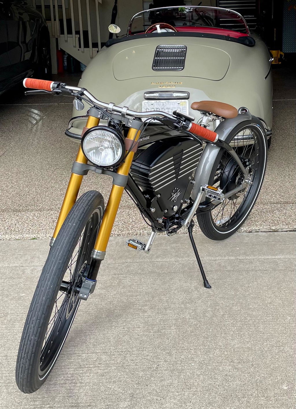 Customer photo of a black Vintage bike with a gold fork in front of a classic car