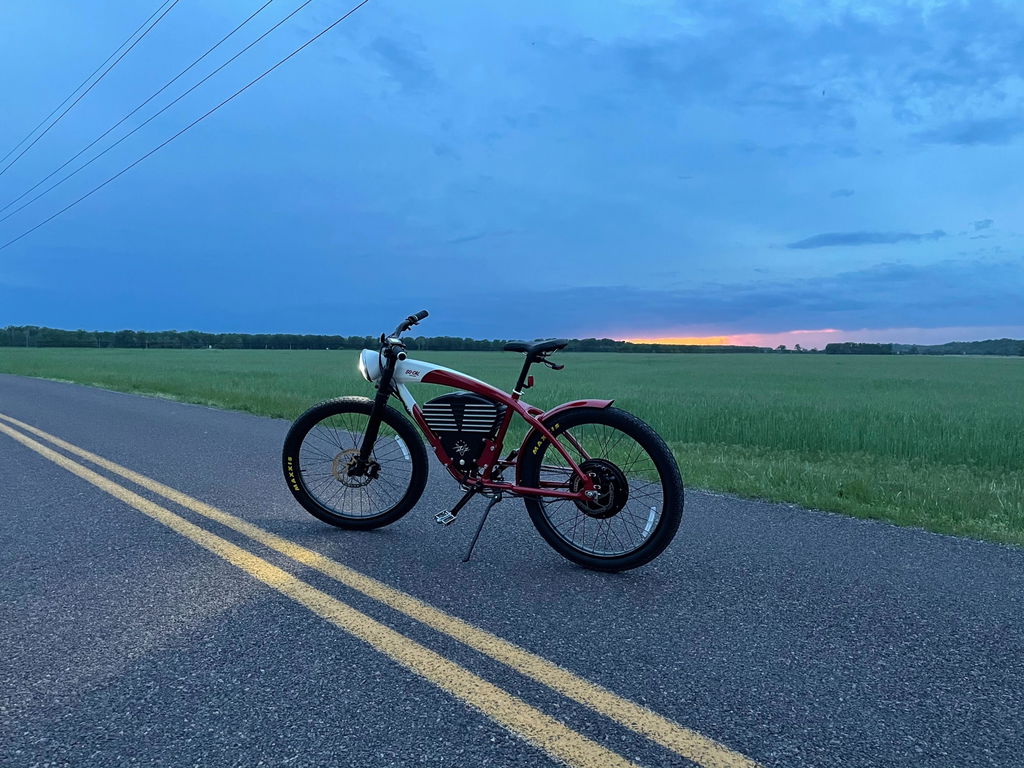 Customer photo of a red and white Roadster on a country road at sunset