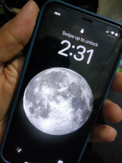 Buyer’s photo: iPhone 12 Pro lock screen with a moon wallpaper, held in hand