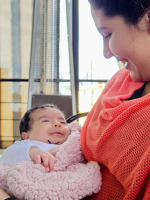 Smiling baby resting on mama in a coral Cocoon